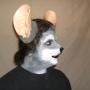 Man wearing foam latex prosthetic nose and makeup to look like an anthropomorphic grey rat.