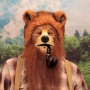 Man wearing latex prosthetic nose and makeup to look like an anthropomorphic brown grizzly bear smoking a pipe