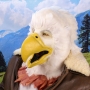 Man wearing latex prosthetic beak and makeup with feathers to look like an anthropomorphic bald eagle.
