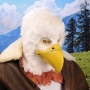 Man wearing latex prosthetic beak and makeup with feathers to look like an anthropomorphic bald eagle.