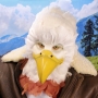 Man wearing latex prosthetic beak and makeup with feathers to look like an anthropomorphic bald eagle.