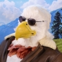 Man wearing latex prosthetic beak and makeup with feathers to look like an anthropomorphic bald eagle with sunglasses.