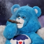 Man wearing latex prosthetic nose and makeup to look like an anthropomorphic Grumpy Bear smoking a cigar