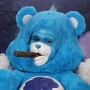 Man wearing latex prosthetic nose and makeup to look like an anthropomorphic Grumpy Bear smoking a cigar