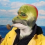 Man wearing foam latex prosthetic face and makeup to look like an anthropomorphic salmon smoking a pipe