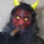 Man wearing foam latex prosthetic nose and makeup to look like a red demonic goat with gold eyes and smoking a cigar Man wearing foam latex prosthetic nose and makeup to look like a red demonic goat with gold eyes and smoking a cigar